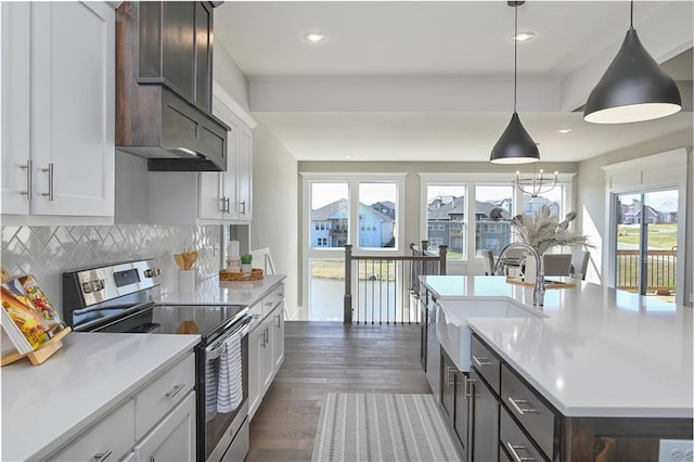 kitchen featuring a sink, light countertops, decorative backsplash, dark wood finished floors, and stainless steel range with electric stovetop