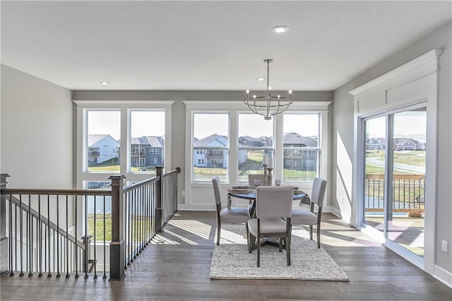 dining room featuring a notable chandelier, recessed lighting, dark wood-type flooring, a residential view, and baseboards