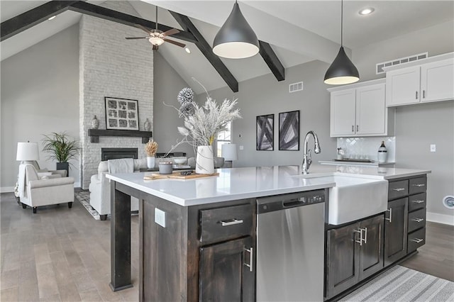 kitchen featuring a fireplace, open floor plan, dishwasher, and light countertops