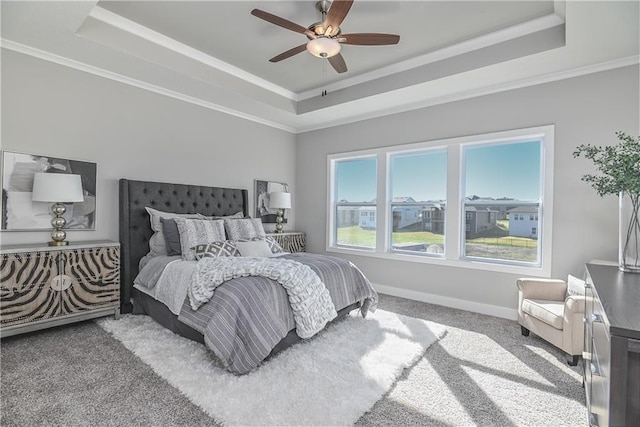 carpeted bedroom featuring ornamental molding, a raised ceiling, baseboards, and a ceiling fan