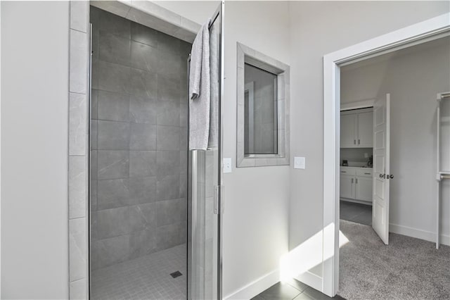 bathroom featuring tile patterned floors, a shower stall, and baseboards