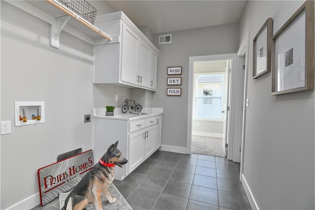 washroom with hookup for a washing machine, cabinet space, hookup for an electric dryer, dark tile patterned flooring, and baseboards