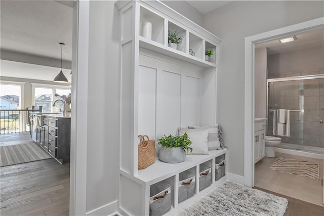 mudroom featuring a sink, baseboards, and wood finished floors