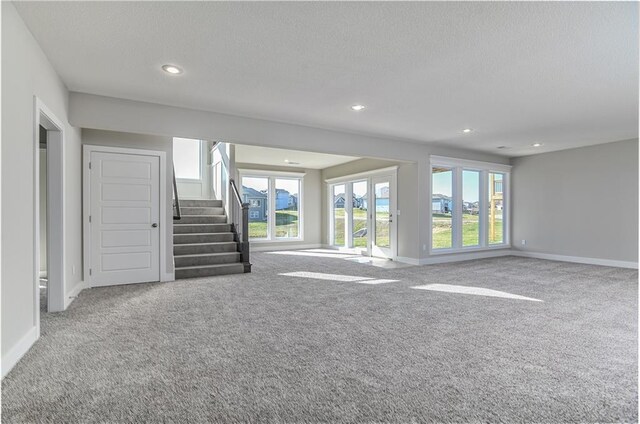 unfurnished living room featuring recessed lighting, carpet flooring, stairway, and baseboards