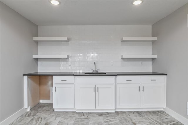 kitchen with dark countertops, backsplash, open shelves, and a sink