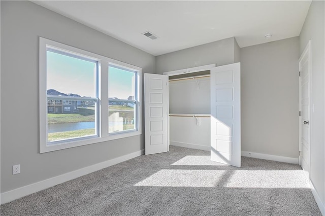 unfurnished bedroom with baseboards, a closet, visible vents, and carpet flooring