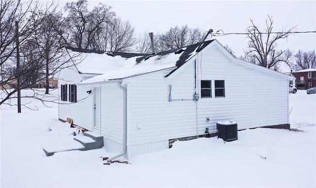 snow covered property featuring a garage, central AC, and entry steps