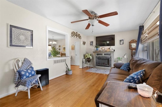 living area with a fireplace with flush hearth, ceiling fan with notable chandelier, baseboards, and wood finished floors