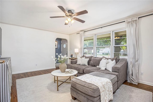 living room with a ceiling fan, arched walkways, wood finished floors, and baseboards