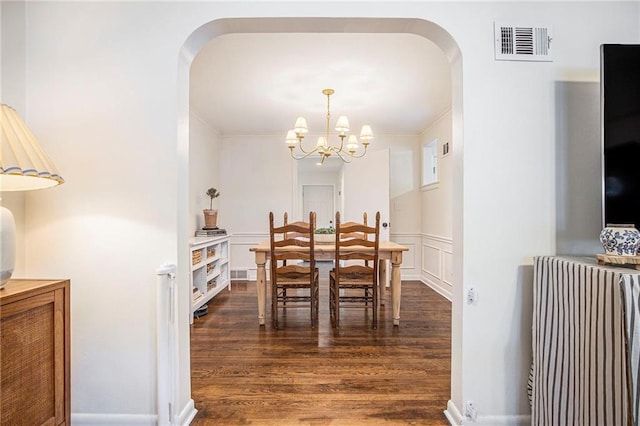 dining room featuring arched walkways, a chandelier, and dark wood-style flooring