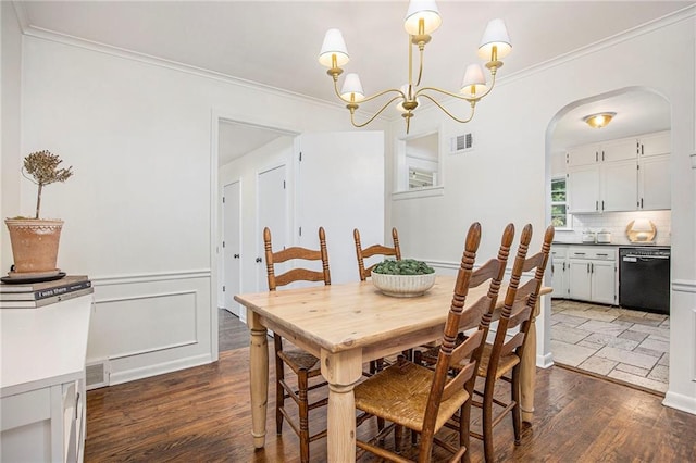dining room featuring arched walkways, dark wood finished floors, a chandelier, and ornamental molding