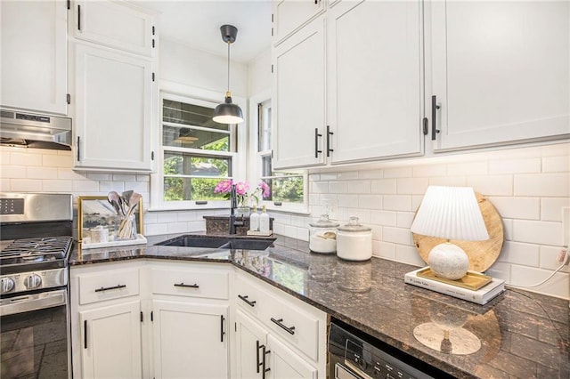 kitchen with stainless steel gas stove, under cabinet range hood, a sink, and white cabinets