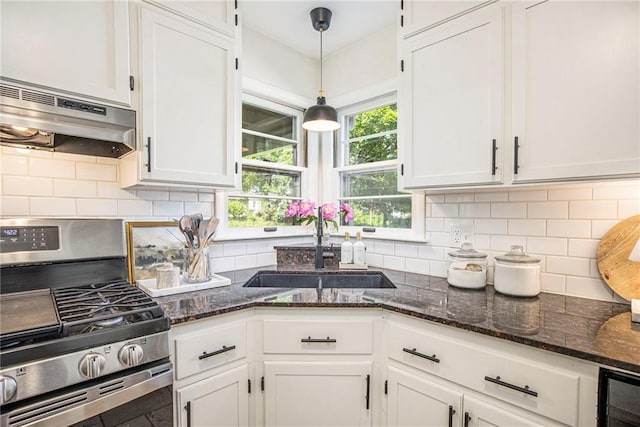 kitchen featuring gas stove, under cabinet range hood, a sink, and white cabinets