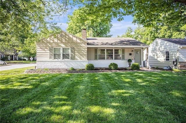 ranch-style home featuring a chimney, a front yard, and brick siding