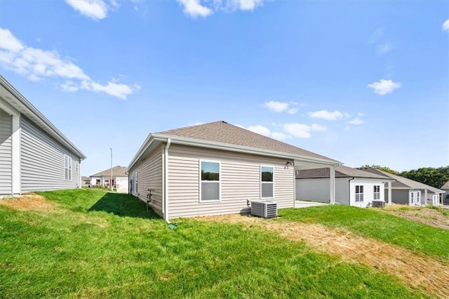 rear view of property with cooling unit and a lawn