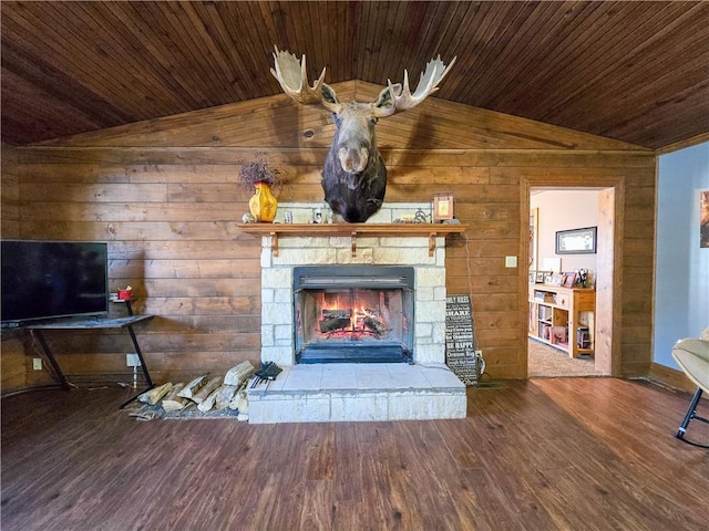 unfurnished living room with vaulted ceiling, a stone fireplace, wooden walls, wood-type flooring, and wood ceiling