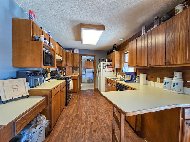 kitchen featuring sink, dark hardwood / wood-style floors, black appliances, a textured ceiling, and kitchen peninsula