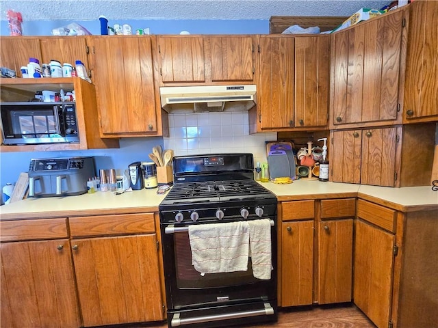 kitchen featuring a textured ceiling, decorative backsplash, and black gas range oven