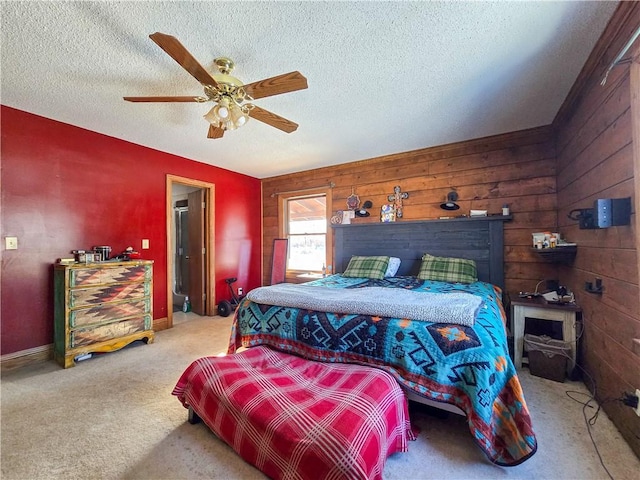 bedroom with ceiling fan, light colored carpet, a textured ceiling, and wood walls