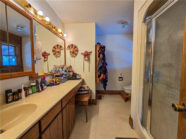 bathroom featuring walk in shower, vanity, toilet, and a textured ceiling