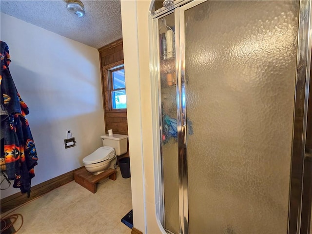 bathroom featuring a shower with door, a textured ceiling, and toilet