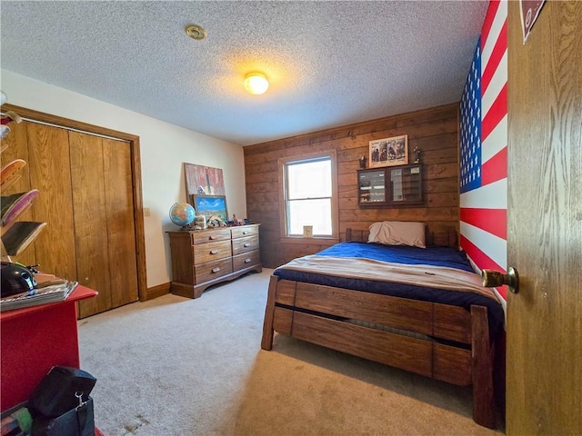 bedroom with wooden walls, light colored carpet, and a textured ceiling