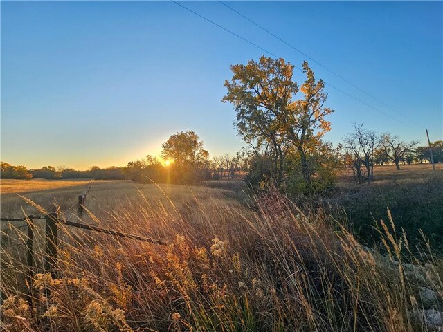 yard at dusk featuring a rural view