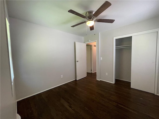 unfurnished bedroom featuring dark wood-style flooring, a closet, a ceiling fan, and baseboards