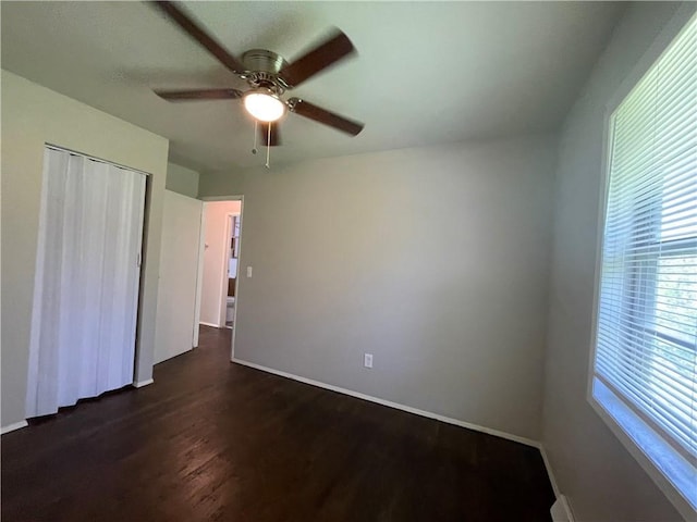 unfurnished bedroom featuring baseboards, a closet, a ceiling fan, and dark wood-style flooring