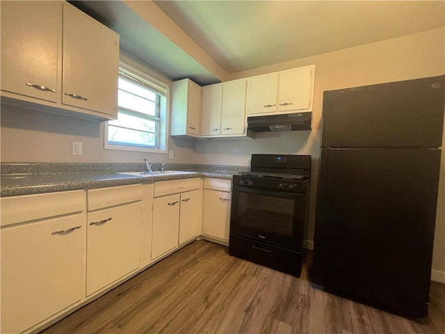 kitchen with dark countertops, under cabinet range hood, black appliances, white cabinetry, and a sink