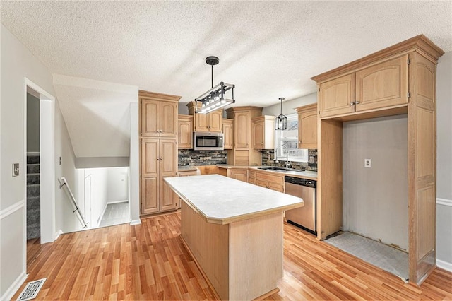 kitchen with visible vents, a center island, stainless steel appliances, light countertops, and pendant lighting