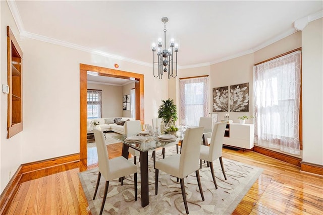 dining room featuring crown molding, a chandelier, light hardwood / wood-style floors, and a wealth of natural light