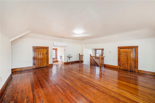 additional living space with hardwood / wood-style flooring and a wall unit AC