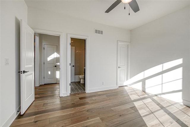unfurnished bedroom with visible vents, baseboards, ensuite bath, and wood finished floors