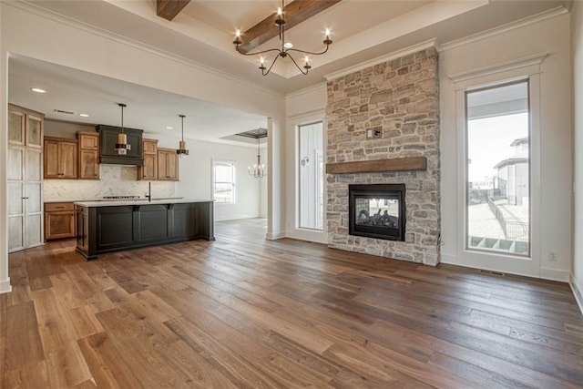 unfurnished living room with a stone fireplace, an inviting chandelier, and dark wood finished floors