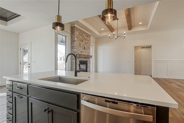 kitchen with open floor plan, light wood-style flooring, an island with sink, stainless steel dishwasher, and a sink