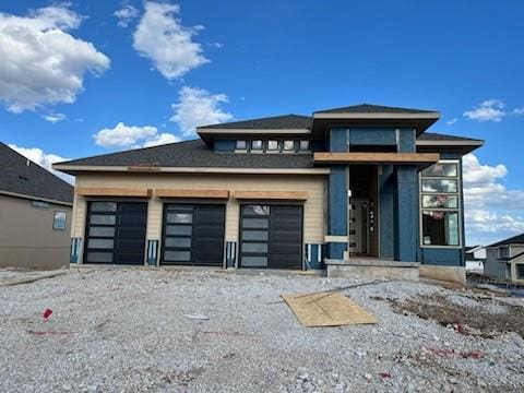 prairie-style home with an attached garage and gravel driveway