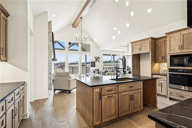 kitchen with an inviting chandelier, black microwave, beam ceiling, stainless steel oven, and a sink