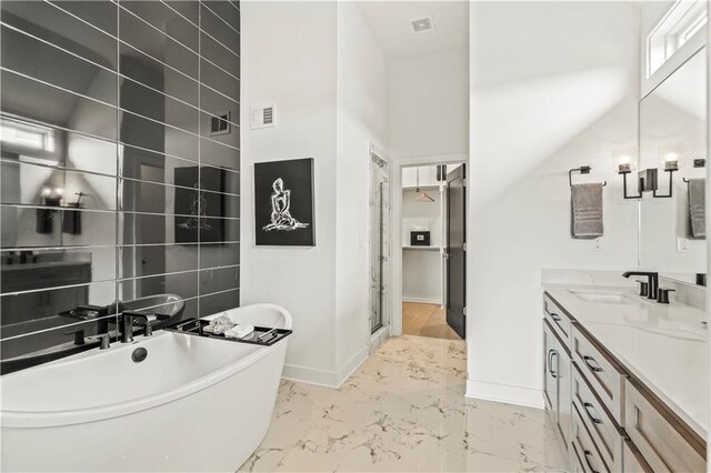 full bath featuring vanity, baseboards, a soaking tub, visible vents, and marble finish floor