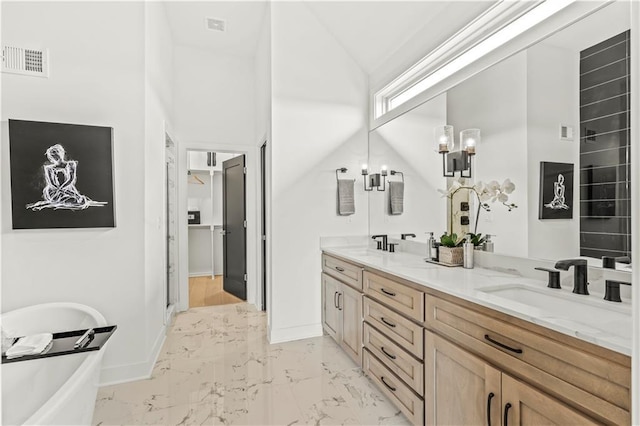 bathroom featuring visible vents, a sink, a soaking tub, double vanity, and marble finish floor