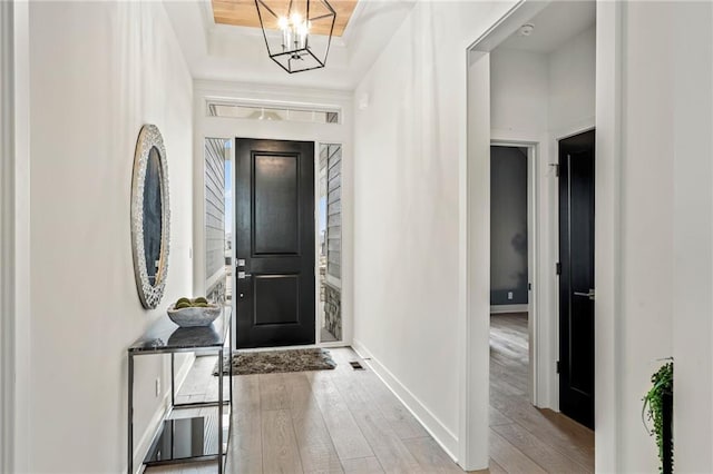 foyer featuring visible vents, baseboards, a chandelier, hardwood / wood-style flooring, and a tray ceiling