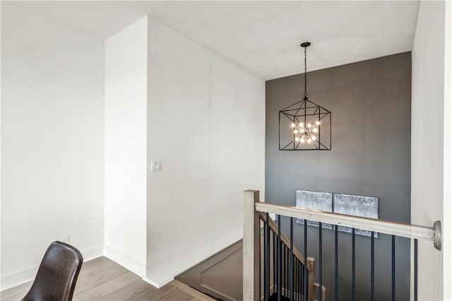 interior space with a chandelier, an upstairs landing, baseboards, and wood finished floors