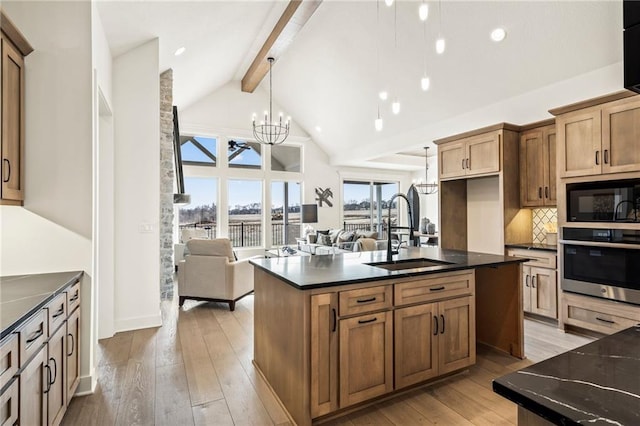 kitchen featuring a notable chandelier, black microwave, beamed ceiling, stainless steel oven, and a sink