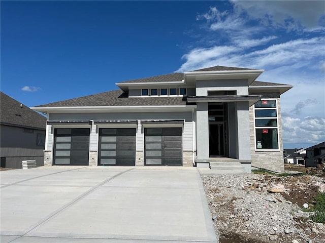 16933 Parkhill St, Overland Park, KS 66221 - prairie-style home featuring driveway, a garage, stone siding, and a shingled roof