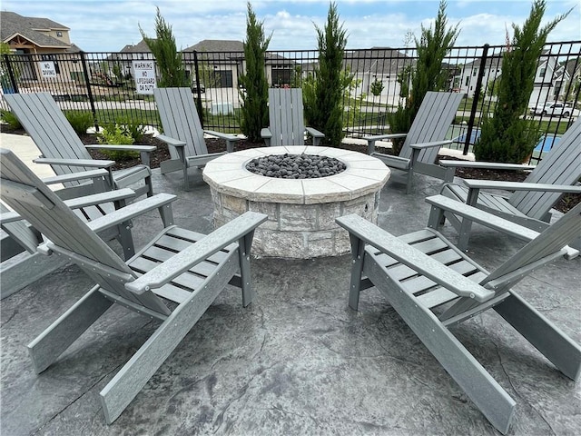 view of patio / terrace featuring an outdoor fire pit, fence, and a residential view