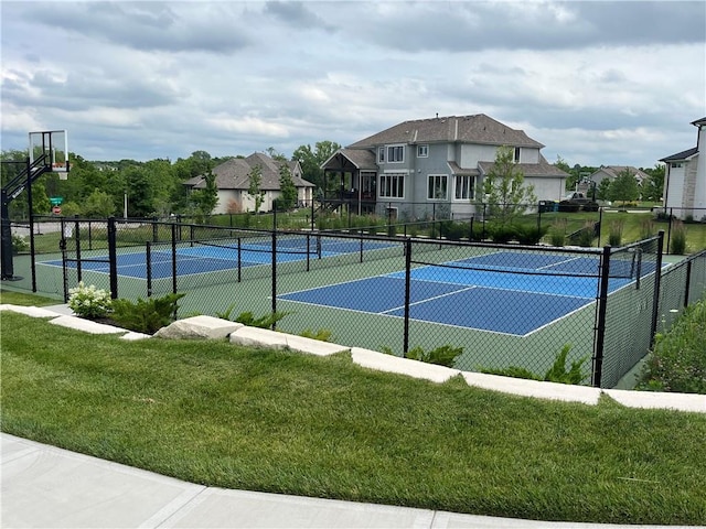 view of tennis court featuring fence and a lawn