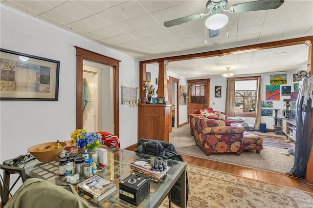 living area with light wood-style floors, ornate columns, and a ceiling fan