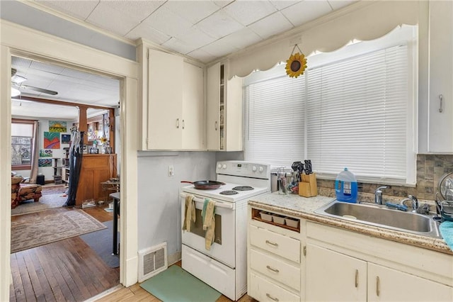 kitchen featuring electric range, visible vents, light countertops, and cream cabinetry