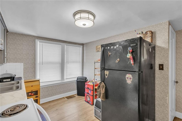 kitchen with visible vents, freestanding refrigerator, light countertops, light wood-style floors, and a sink