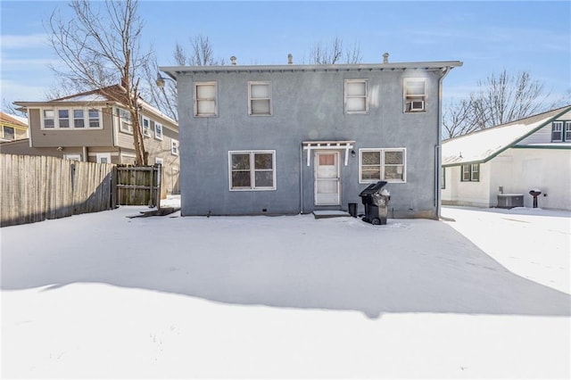 snow covered property with central air condition unit, fence, and stucco siding